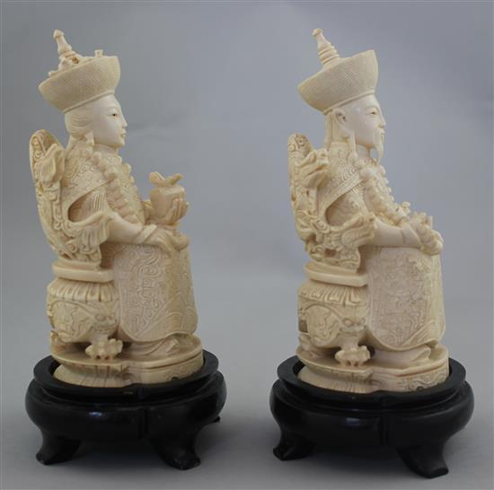 A pair of Chinese ivory seated figures of an emperor and empress, first half 20th century, 13.5cm excl. the wood stands